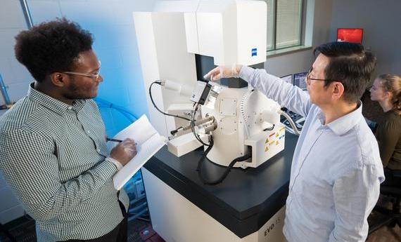 Two people using an electron microscope in 's College of Liberal Arts