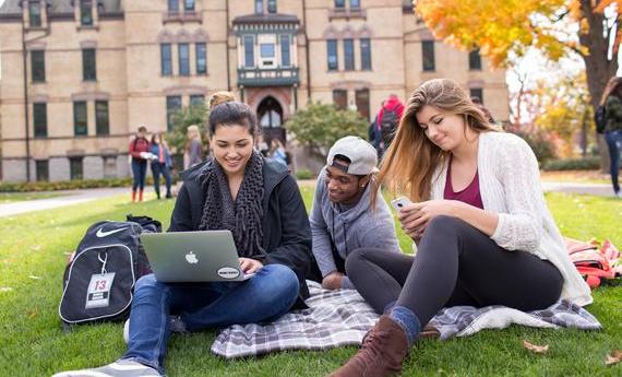 Three  students sitting on a blanket on the grass outside Old Main