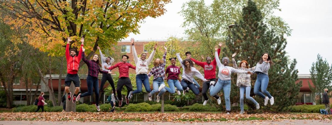 A group of  students in a line outside, jumping for joy