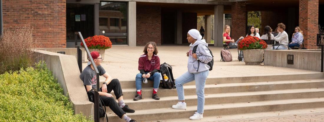 Three  students gathered on a set of outdoor stairs on campus